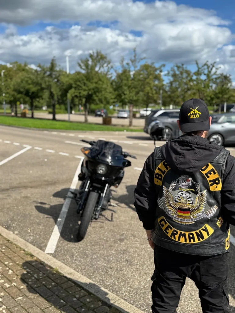 Black Rider Member in Clubweste vor einem schwarzen Motorrad
